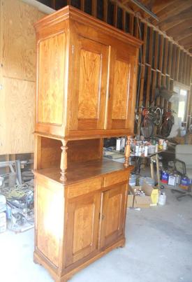 A wooden cabinet in a garage filled with various tools