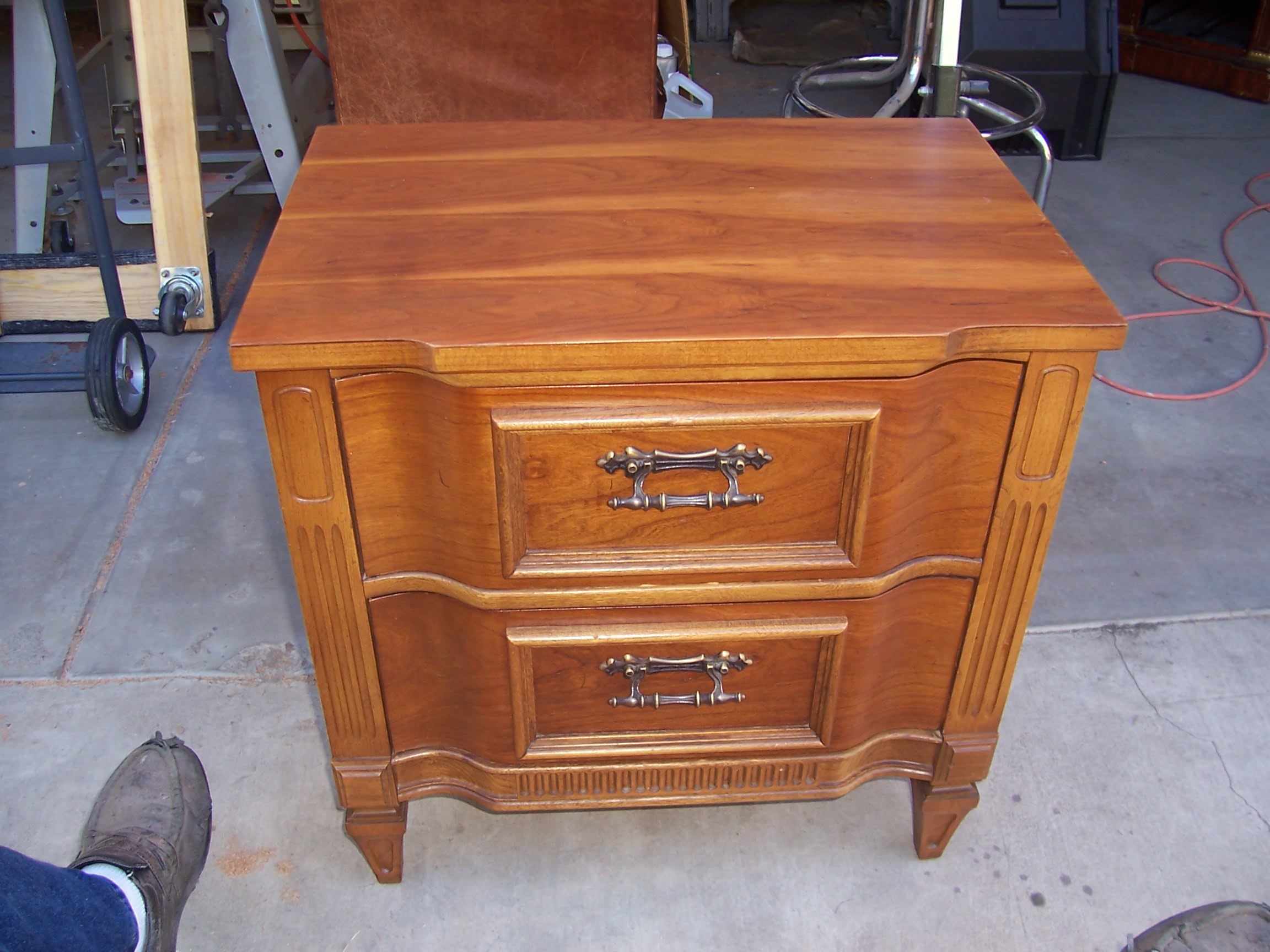 A wooden nightstand featuring two drawers and a sleek metal handle.