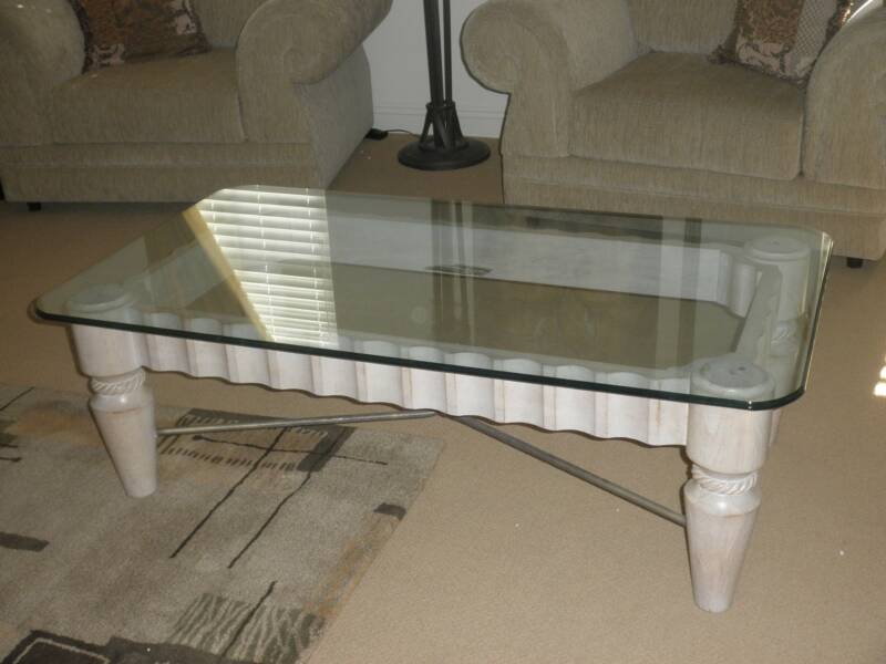 A glass coffee table with a sleek white frame