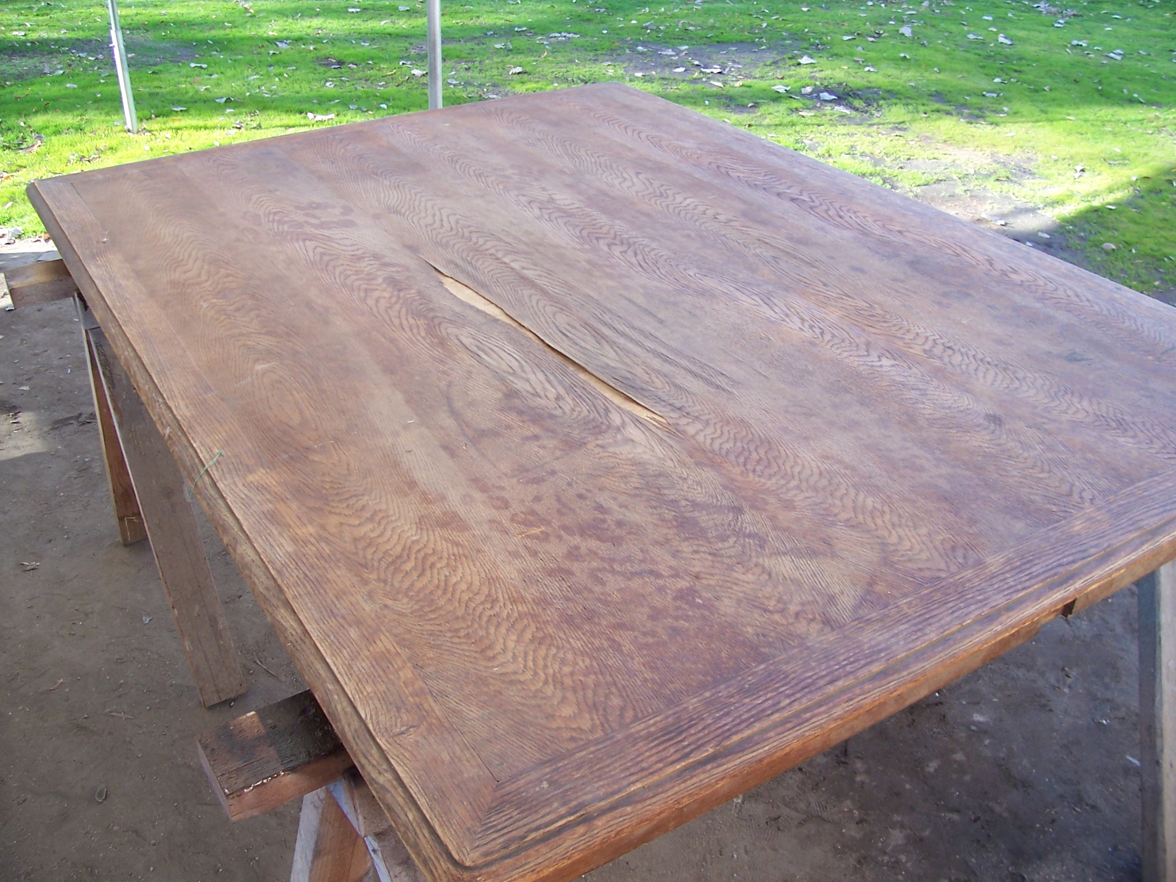 A table with a hole in the center placed on a dirt surface outdoors.